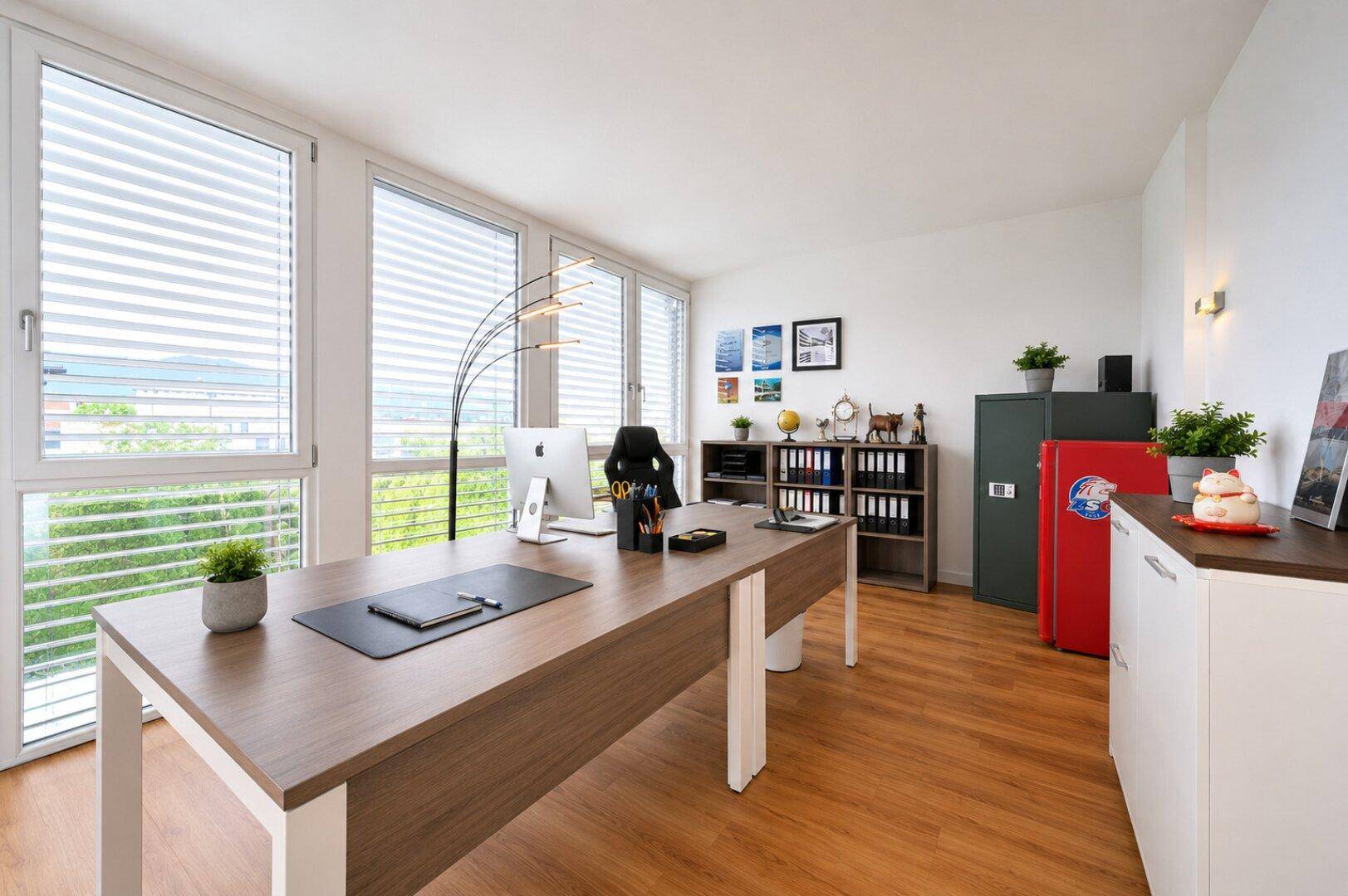 Geräumiges Heimbüro mit großem Schreibtisch, viel Tageslicht und Holzboden.