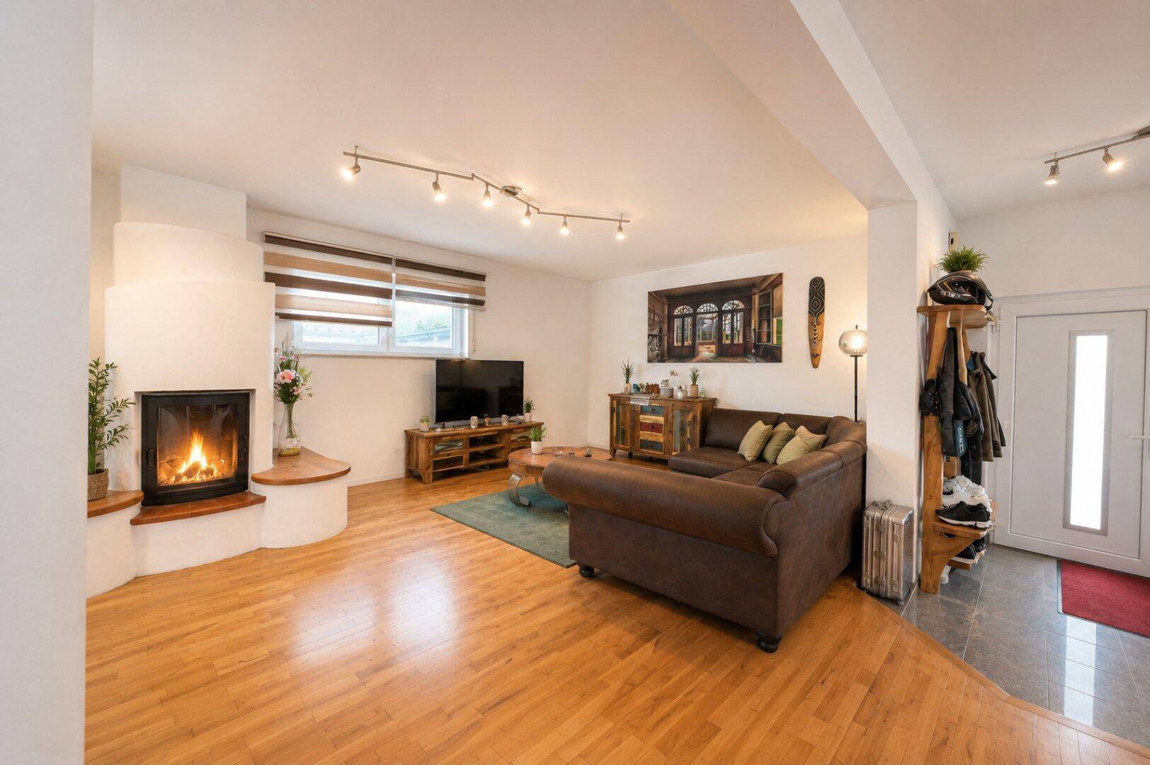Gemütliches Wohnzimmer mit Kamin, Holzboden und bequemer Sitzecke.