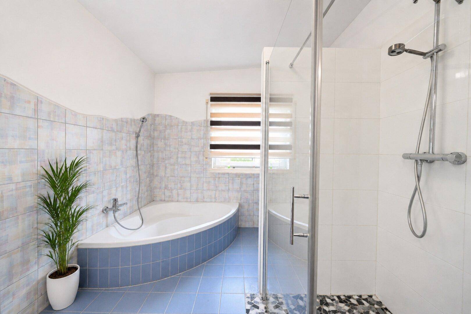 Badezimmer mit blauen Fliesen, Eckbadewanne und begehbarer Dusche.