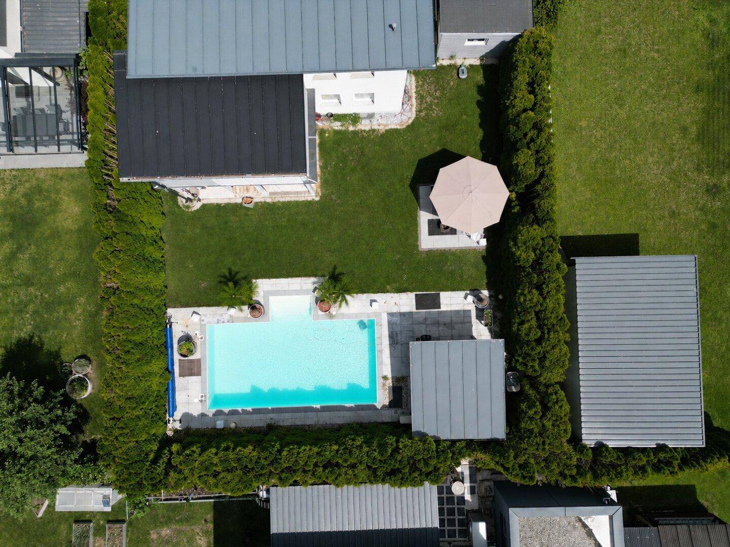 Draufsicht auf ein Grundstück mit Swimmingpool, Rasenfläche und Gartenbereich.