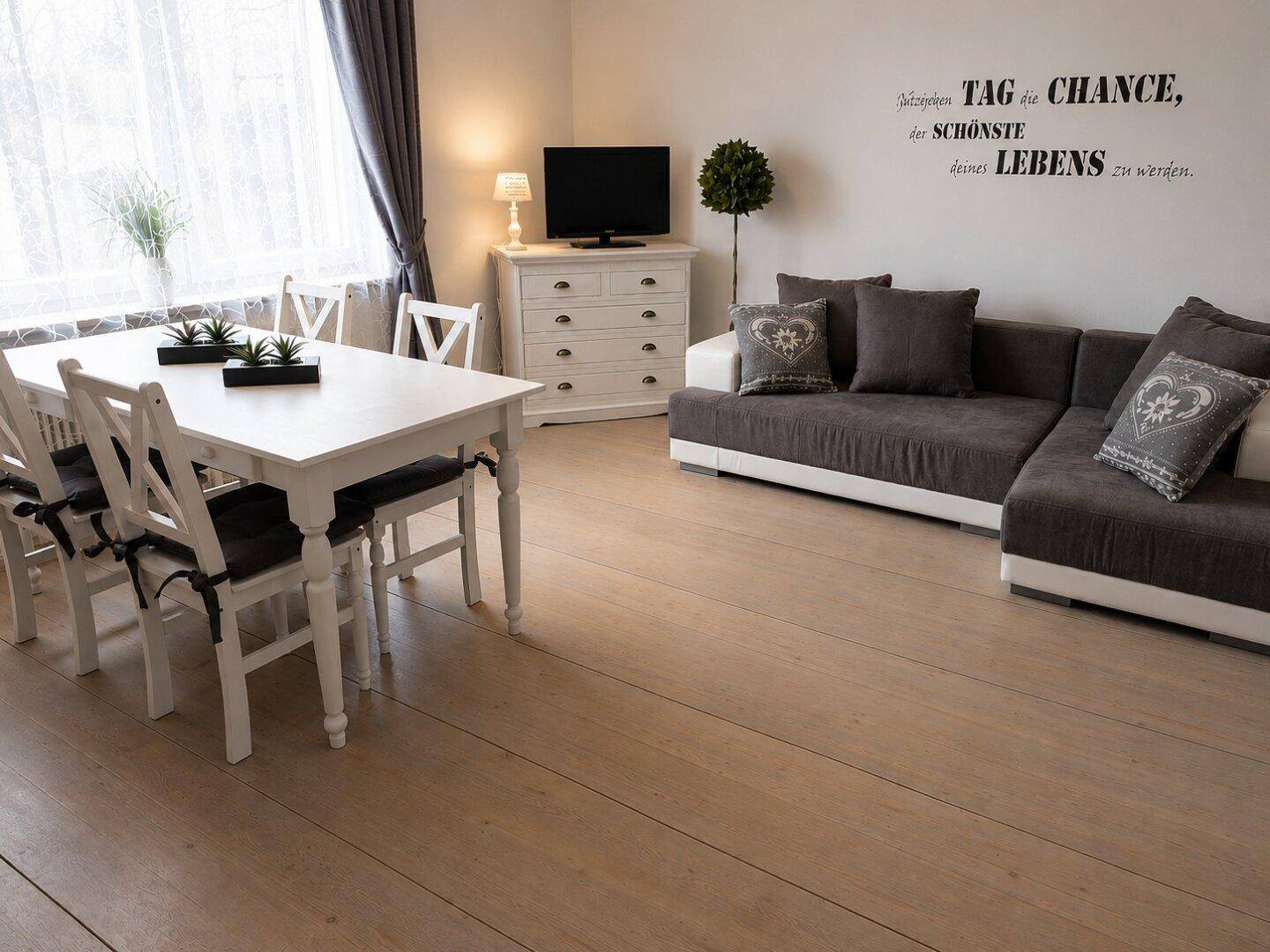 Geräumiger Wohn-Essbereich mit hellem Holzboden, Esstisch und großem Ecksofa.
