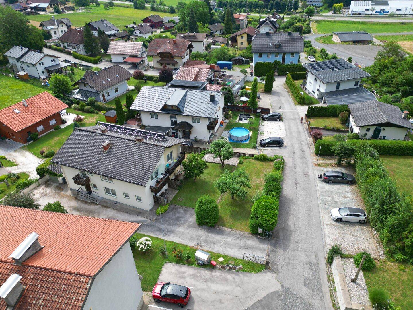 Luftaufnahme einer Wohnsiedlung mit verschiedenen Häusern, Gärten und einem Pool.