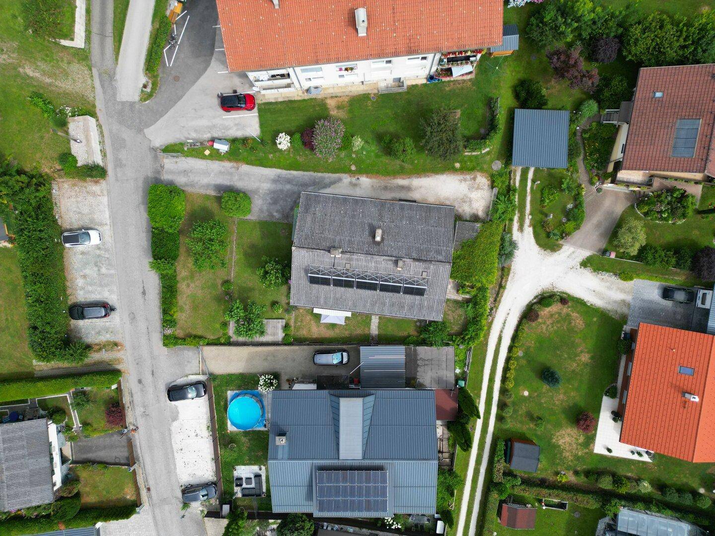 Senkrechte Luftaufnahme von Wohnhäusern mit Gärten, Dächern und Photovoltaikanlagen.