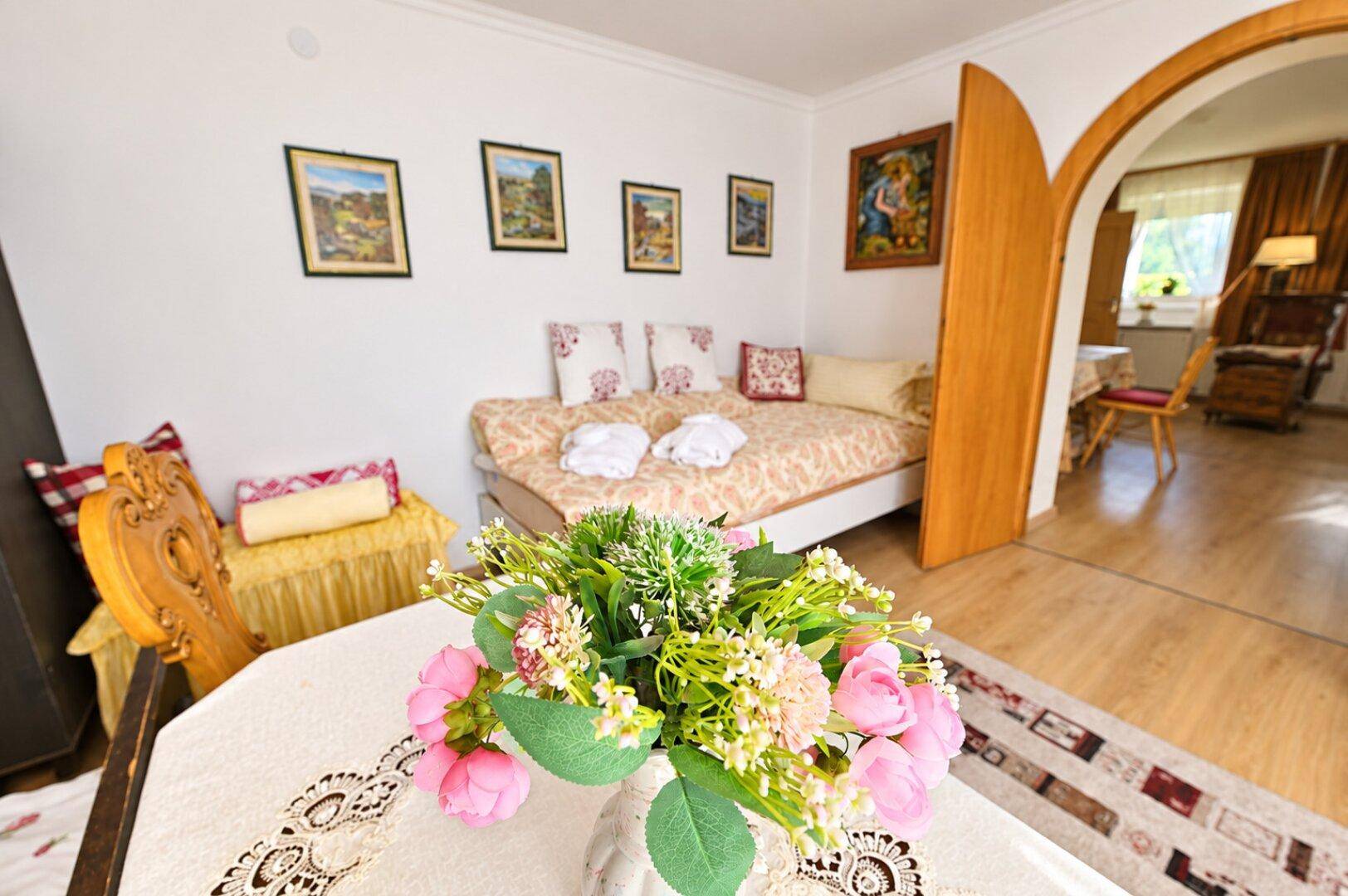 Gemütliches Schlafzimmer mit Tagesbett und traditioneller Dekoration, mit Blick in einen angrenzenden Raum.