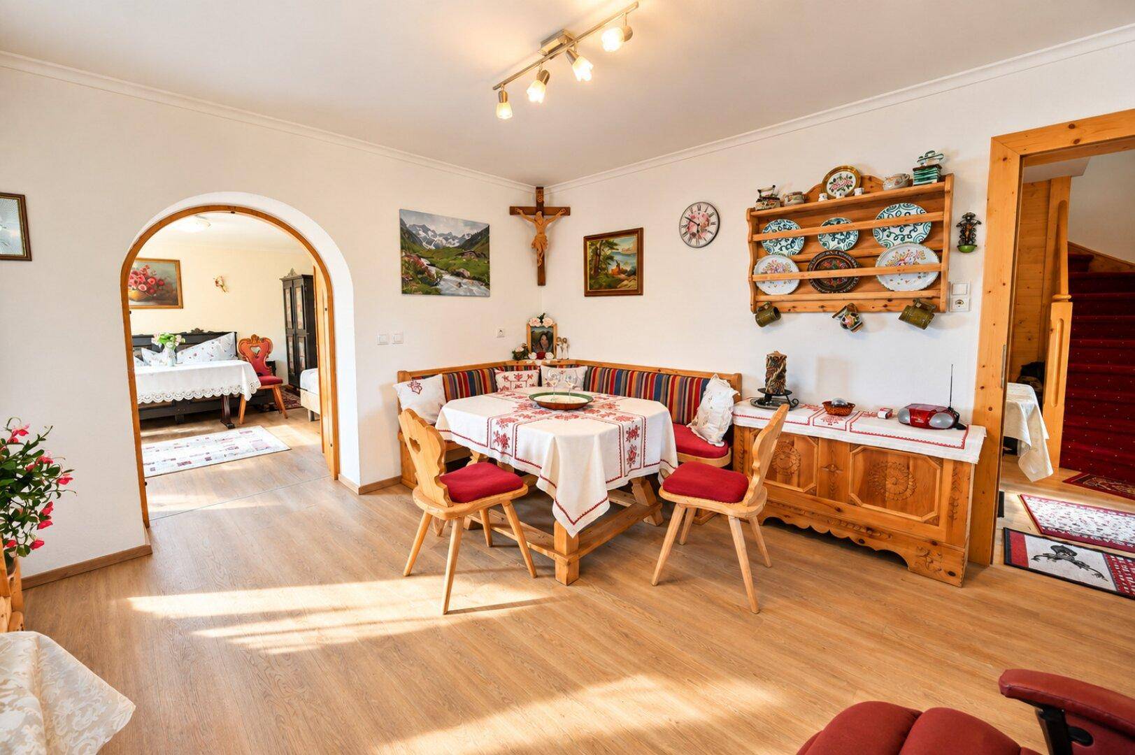 Traditioneller Essbereich mit Holztisch, Eckbank und rustikalen Dekorationen, offen zu einem weiteren Raum.