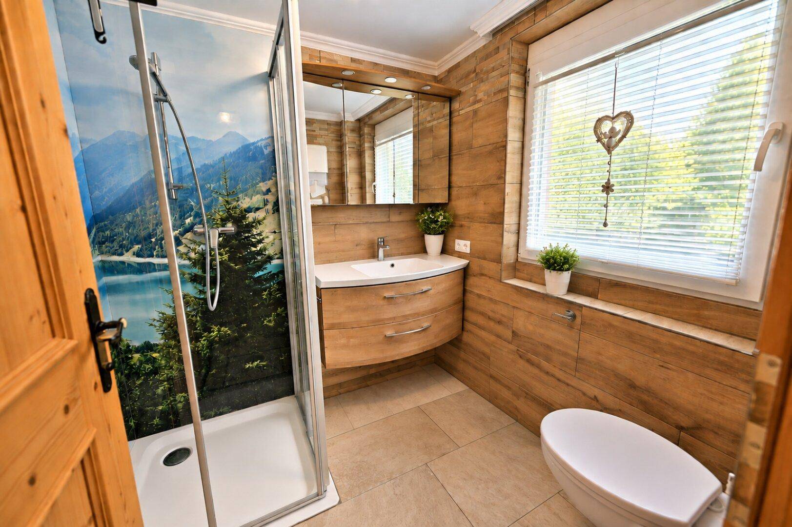 Helles Badezimmer mit Fenster, Duschkabine und Holzverkleidung, ausgestattet mit einem Spiegelschrank.