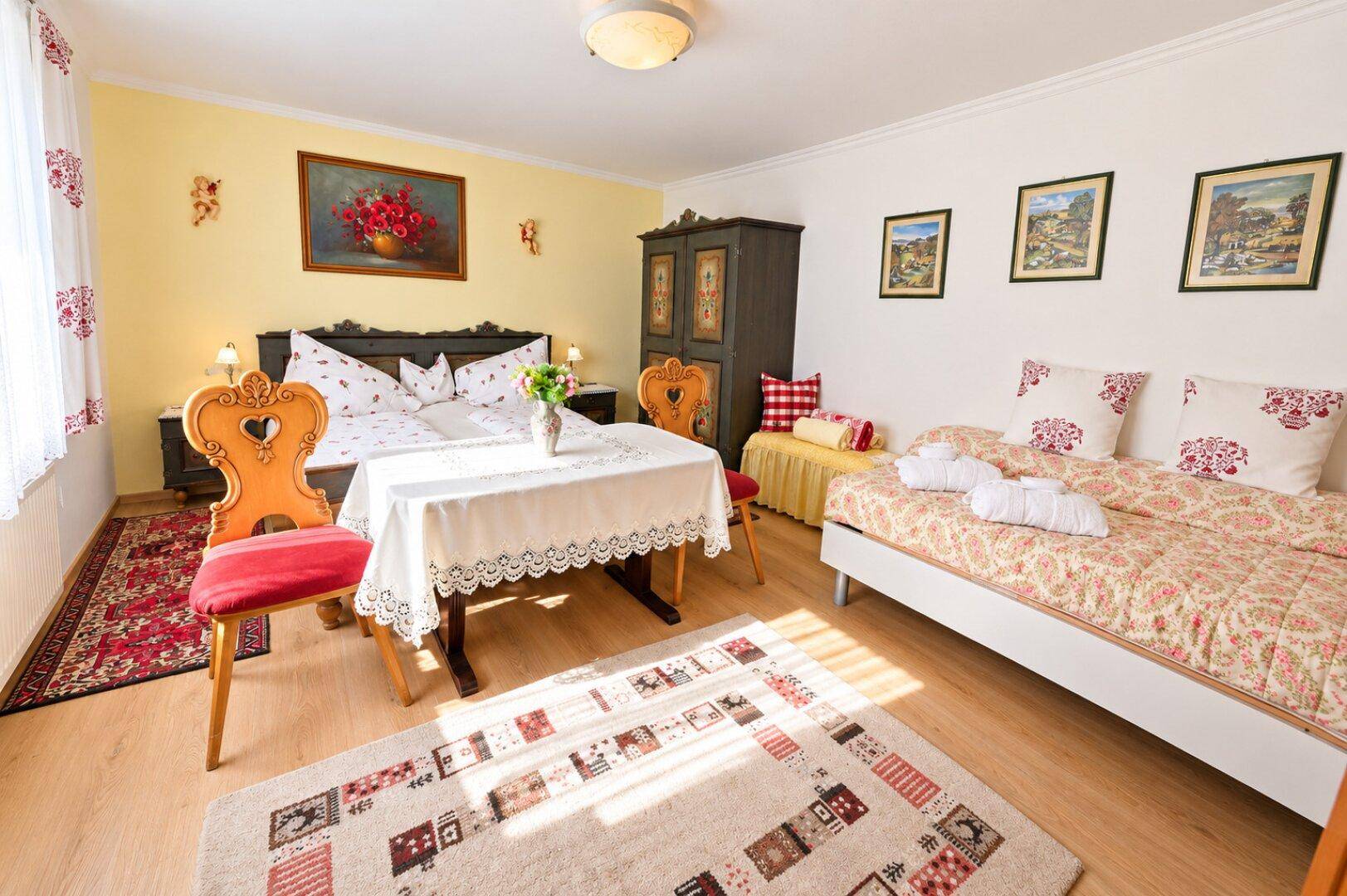 Geräumiges Schlafzimmer im traditionellen Stil mit Doppelbett, Tagesbett und farbenfrohen Textilien.