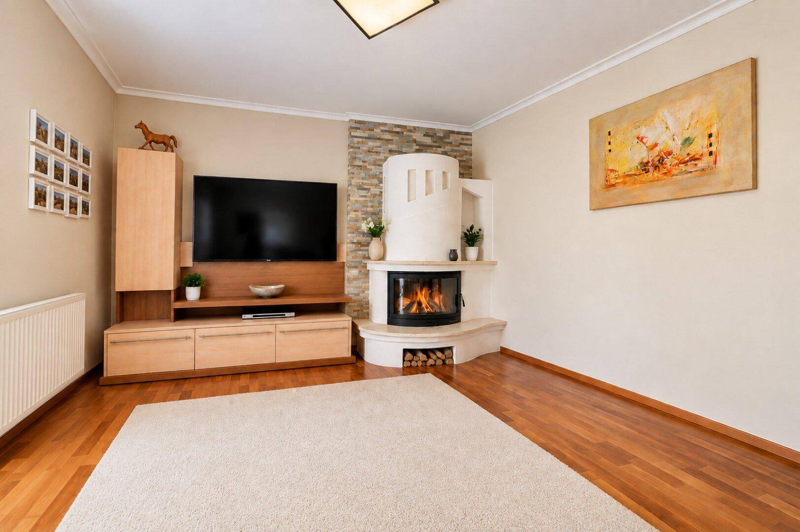 Gemütliches Wohnzimmer mit Holzboden, einem modernen Kamin und einem großen Teppich.