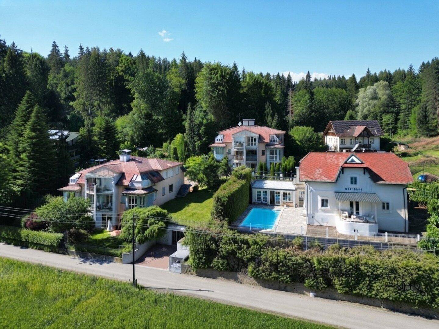 Luftaufnahme von mehreren Villen mit Pool, umgeben von üppiger grüner Landschaft und Wald.