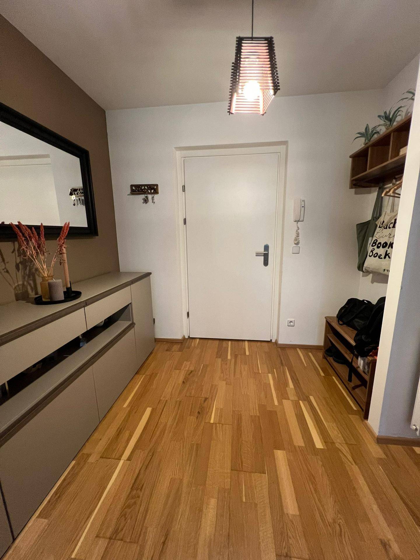Eingangsbereich mit Holzboden, Spiegel, Kommode und Garderobe, einladend gestaltet.