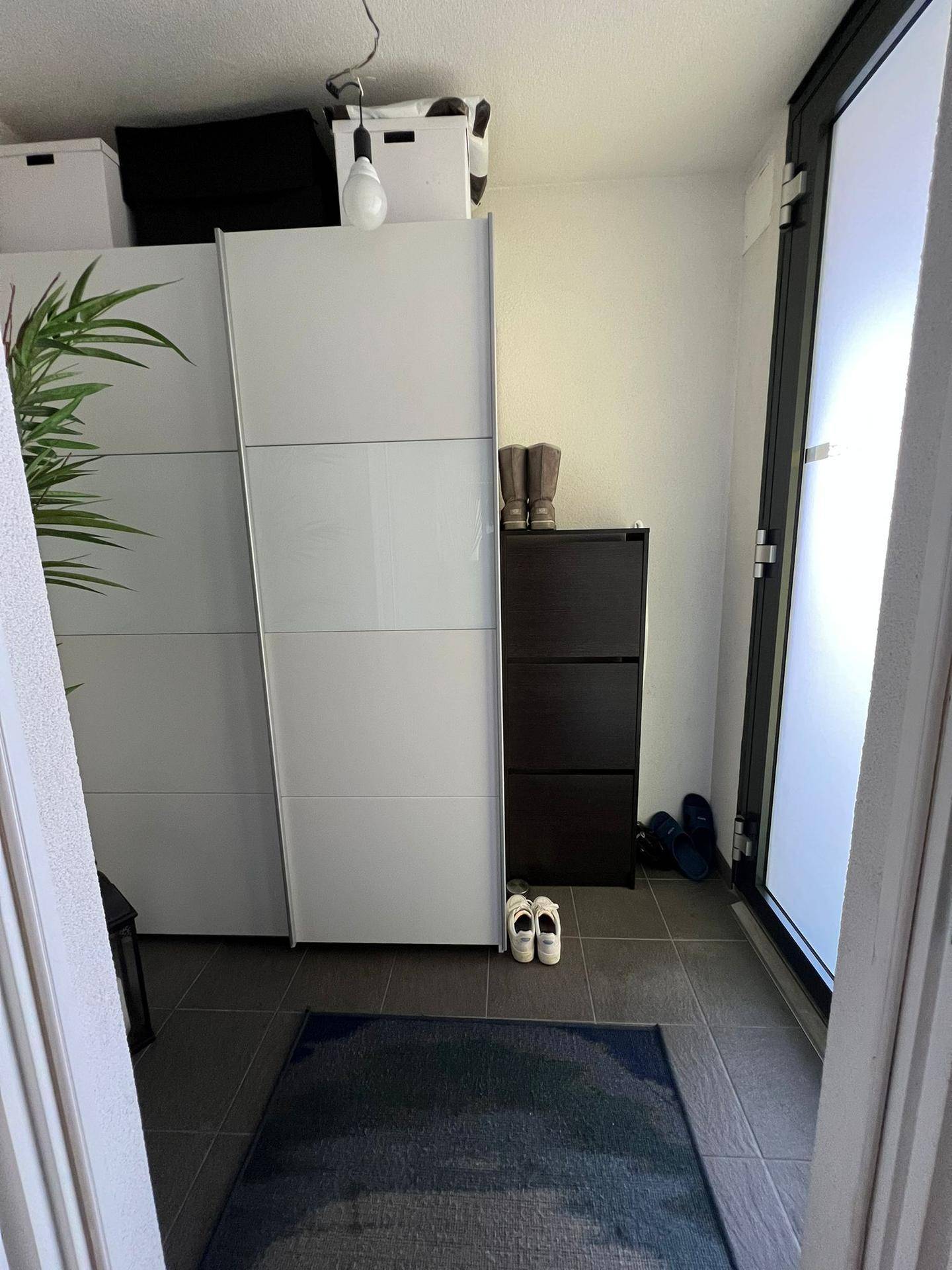 Kleiner Bereich mit Fliesenboden, Schränken und Zugang zu einem Außenbereich.