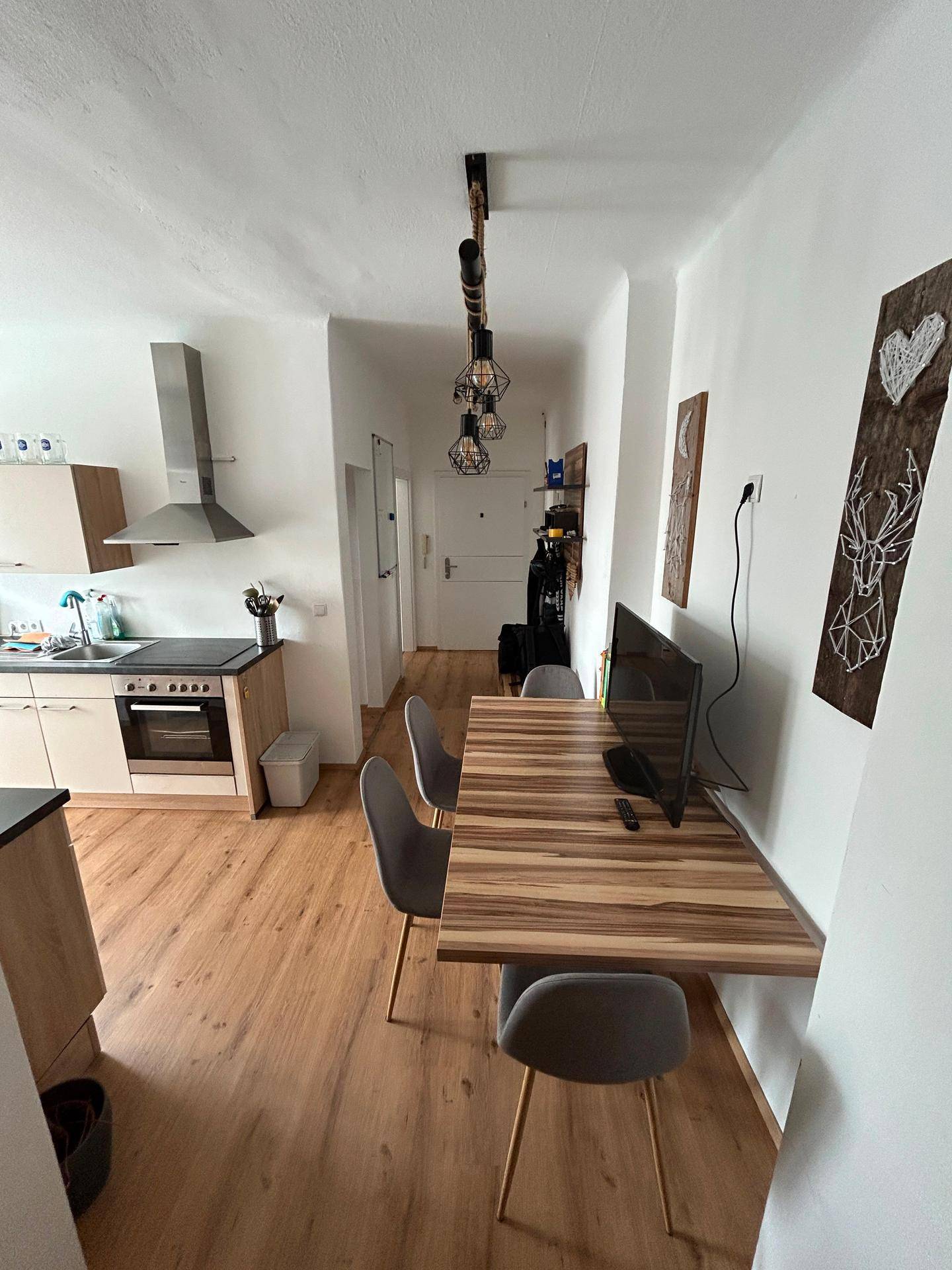 Gemütlicher Essbereich mit Holztisch und Blick auf die moderne Küche und den Flur.
