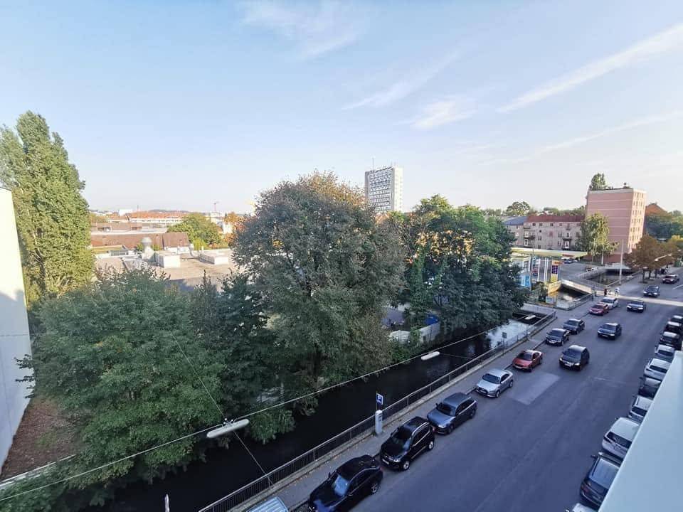 Ausblick vom Balkon auf eine belebte Straße, einen Kanal und städtische Gebäude.