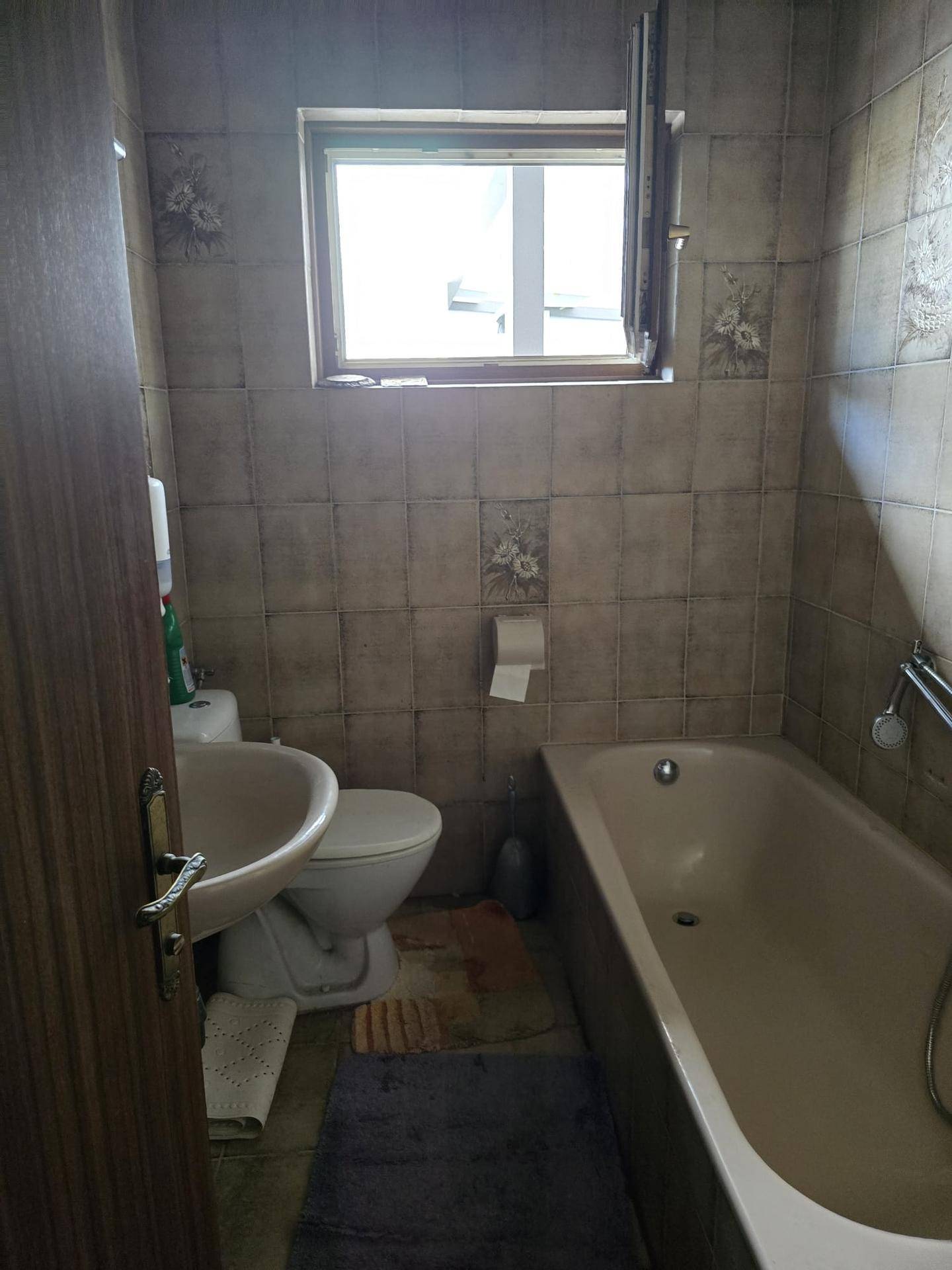 Badezimmer im älteren Stil mit Badewanne, Toilette, Waschbecken und einem Fenster.