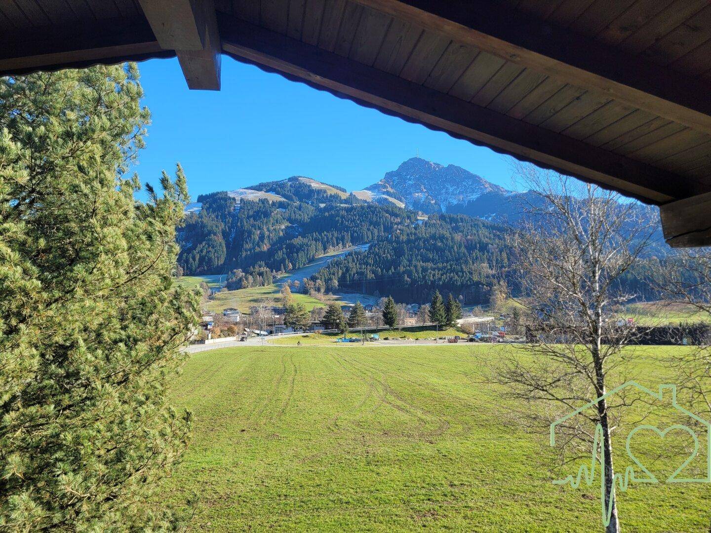Panoramablick von einem Balkon auf grüne Wiesen und die umliegende Berglandschaft.