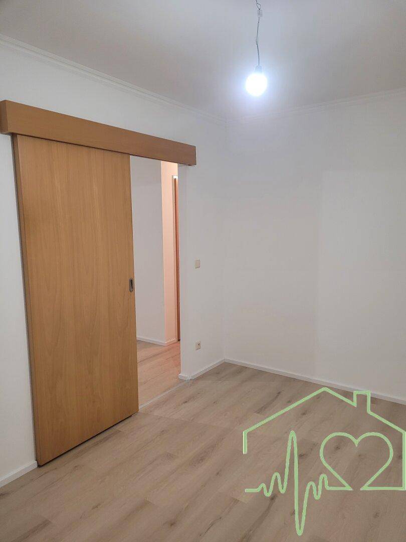 Schlafzimmer mit hellem Laminatboden und einer praktischen Holzschiebetür, die Platz spart.