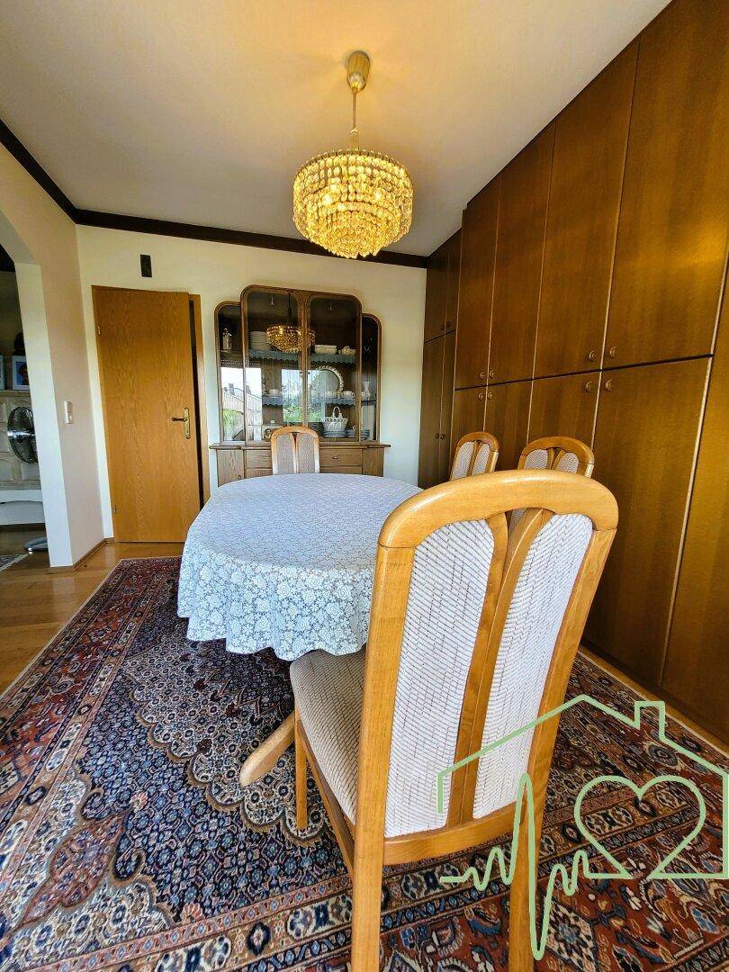 Klassisches Esszimmer mit Holzboden, großem Esstisch und einem Kronleuchter.