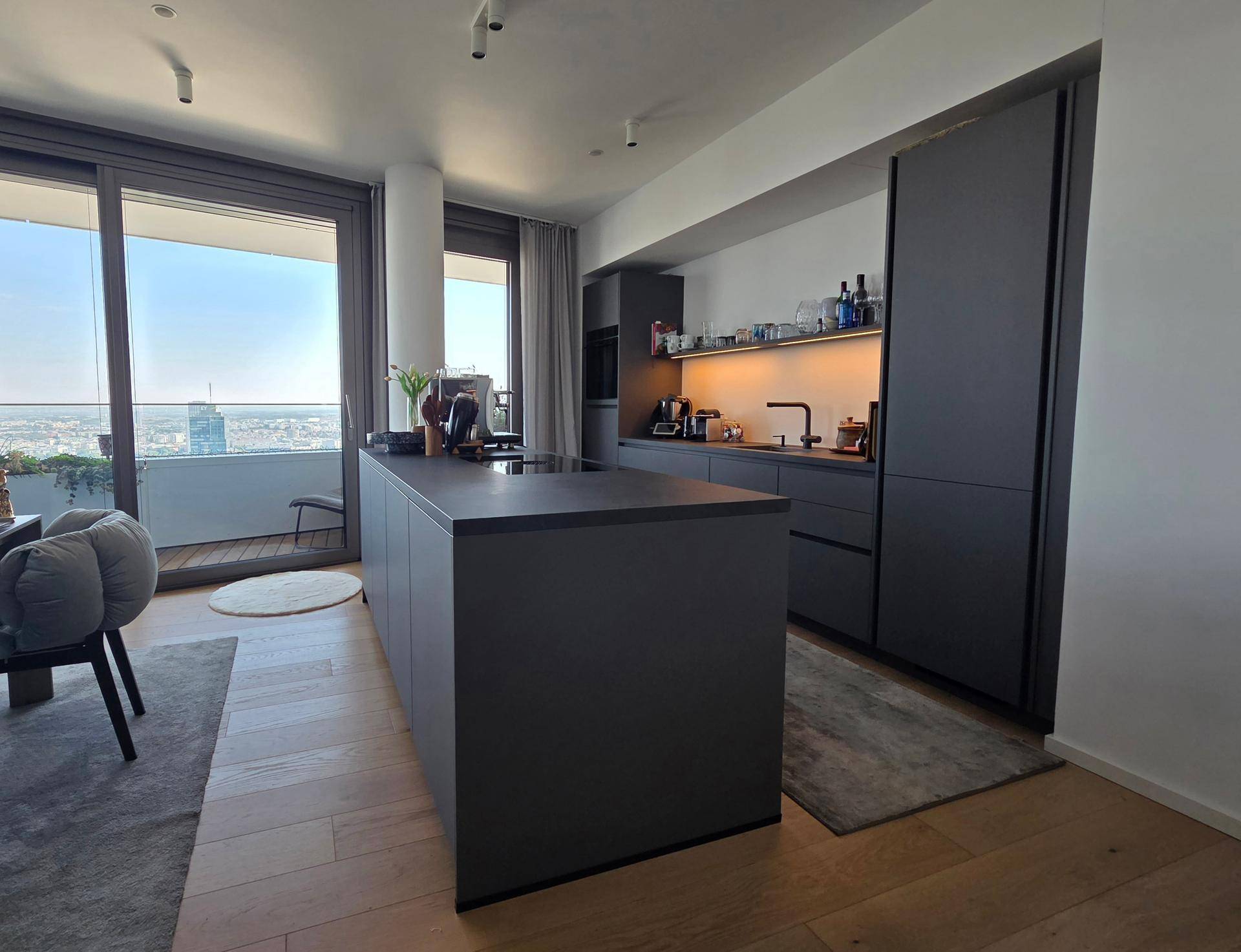 Moderne offene Küche mit dunklen Schränken und Kücheninsel, mit Stadtblick.