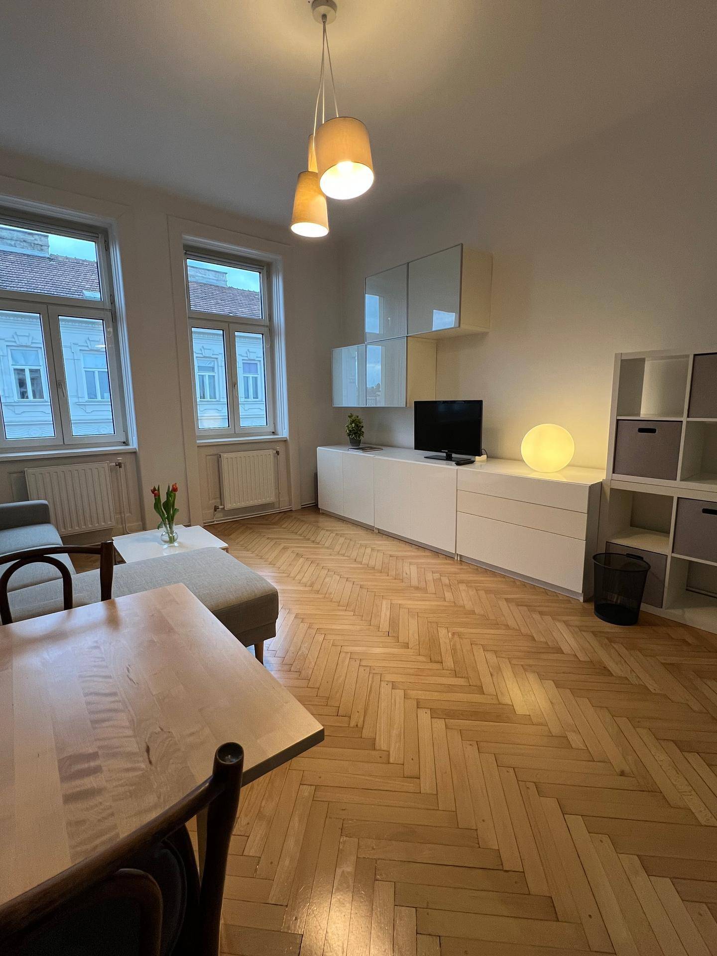 Heller Wohnbereich mit Esstisch, Sofa und großen Fenstern, die den Raum mit Licht füllen.