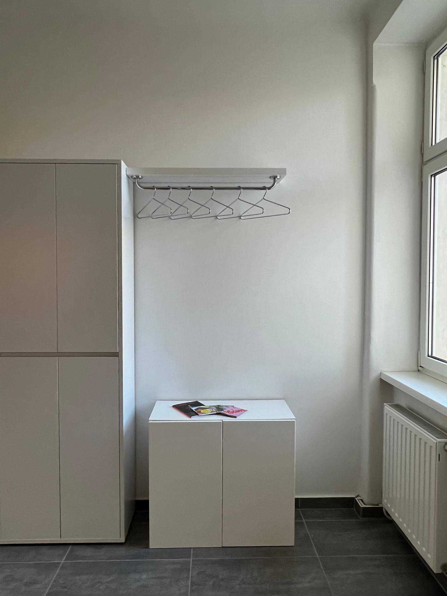 Heller Flur mit Kleiderschrank, Garderobe und Fenster, das den Raum erhellt.