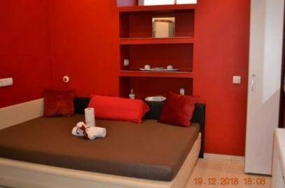 Schlafzimmer mit leuchtend roten Wänden, einem Bett und integrierten Regalen für persönlichen Stauraum.