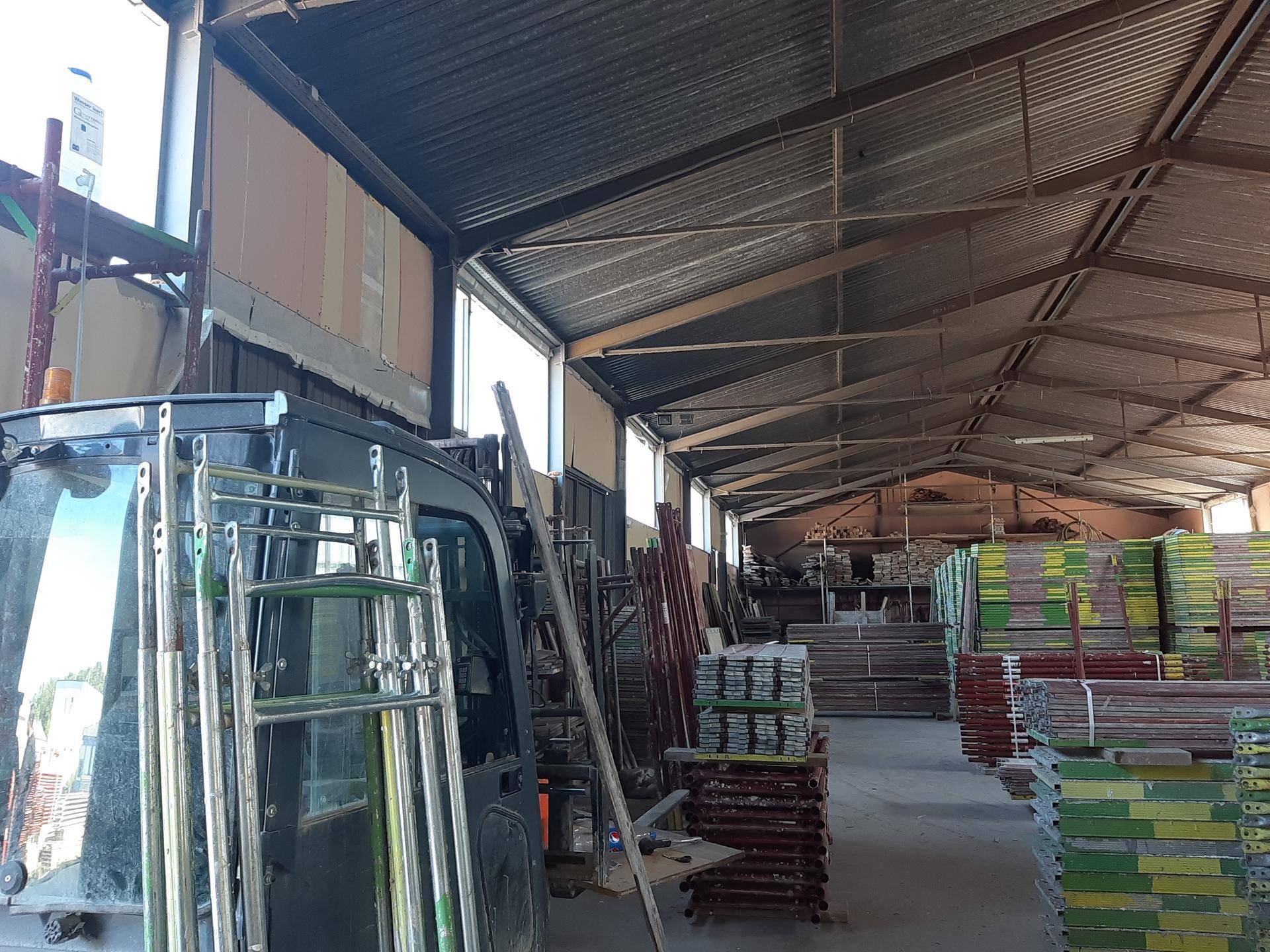 Lagerhalle mit gestapelten Materialien und einem Fahrzeug, das auf dem Betonboden steht.