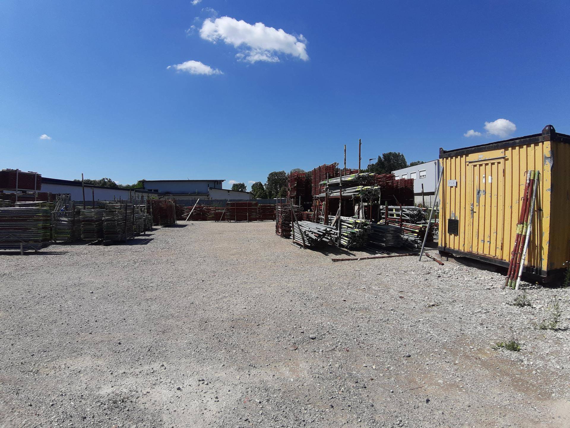 Weitläufiger Schotterplatz im Freien, genutzt zur Lagerung von Baumaterialien und Containern.