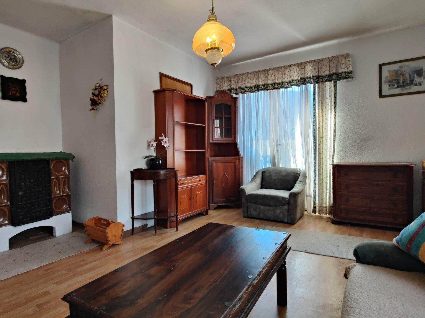 Wohnzimmer mit Holzboden, traditionellem Kachelofen und klassischer Einrichtung.