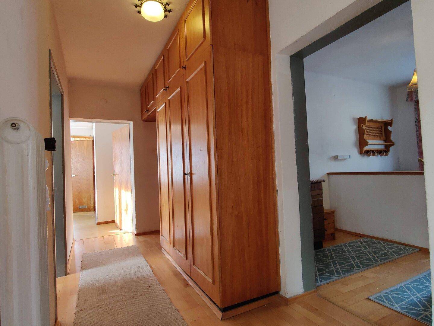 Heller Flur mit Einbauschränken aus Holz und Parkettboden.