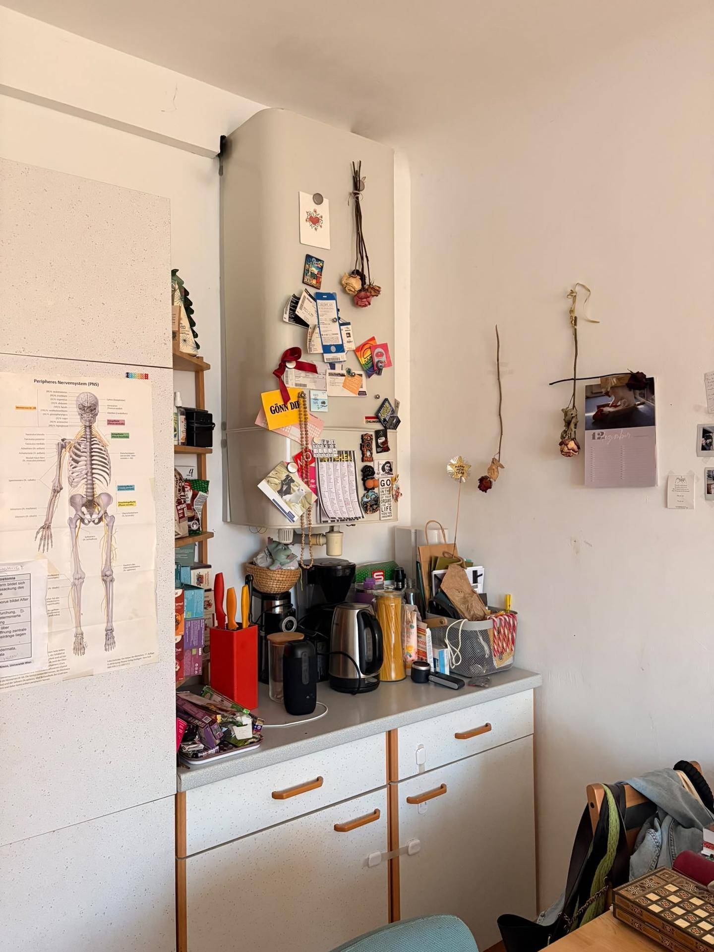 Kleine Küchenzeile mit Arbeitsplatte, Spüle und verschiedenen Küchengeräten, über der ein Boiler hängt.