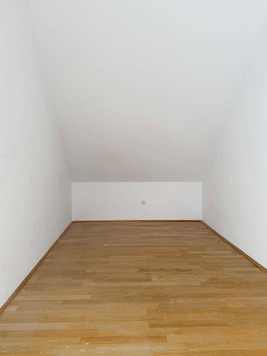 Leerer Raum mit schräger Decke und hellem Holzboden, ideal als Abstellraum nutzbar.