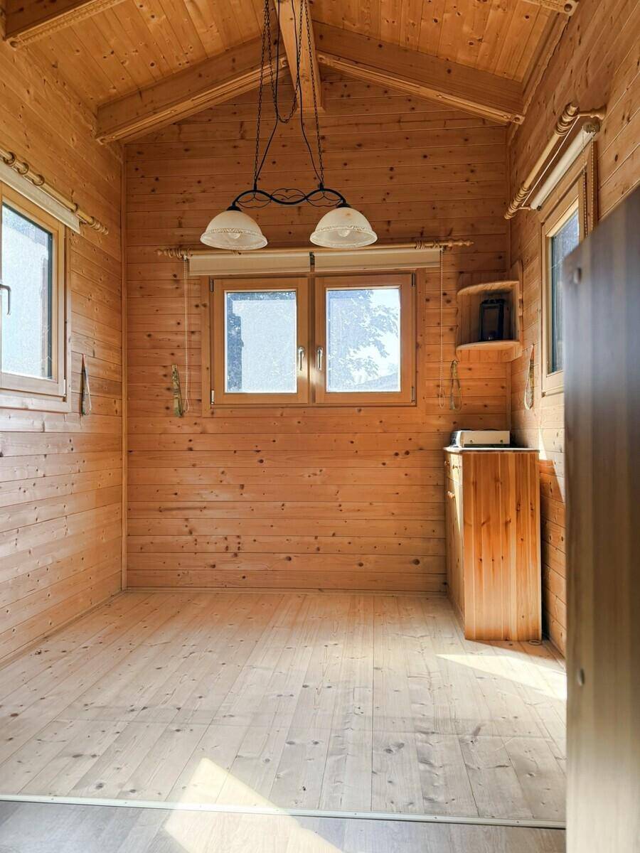 Lichtdurchfluteter Raum mit Holzboden, Holzvertäfelung und schrägen Decken, ideal als Schlafzimmer.