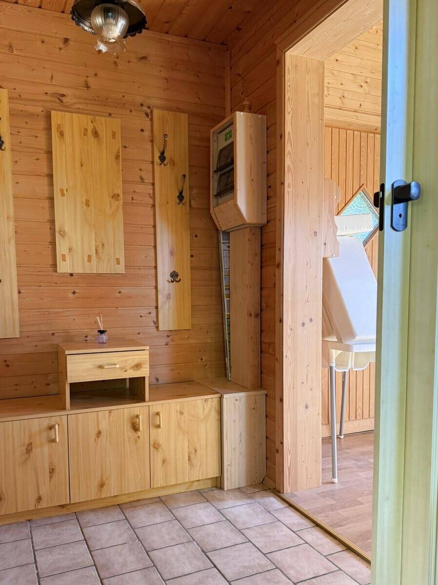 Eingangsbereich mit gefliestem Boden, Holzvertäfelung und einer Garderobe aus hellem Holz.