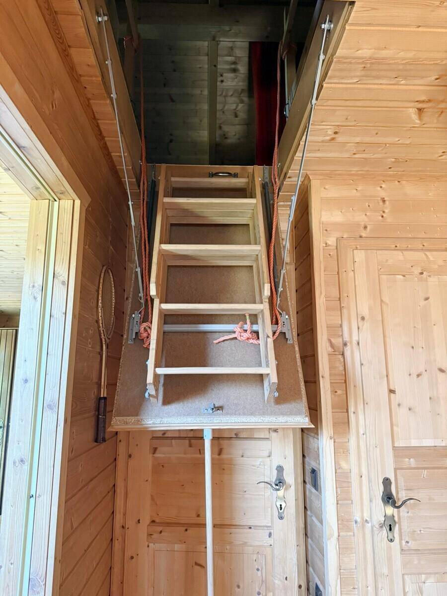 Ausziehbare Dachbodenleiter, die den Zugang zu einem oberen Stauraum im Holzhaus ermöglicht.