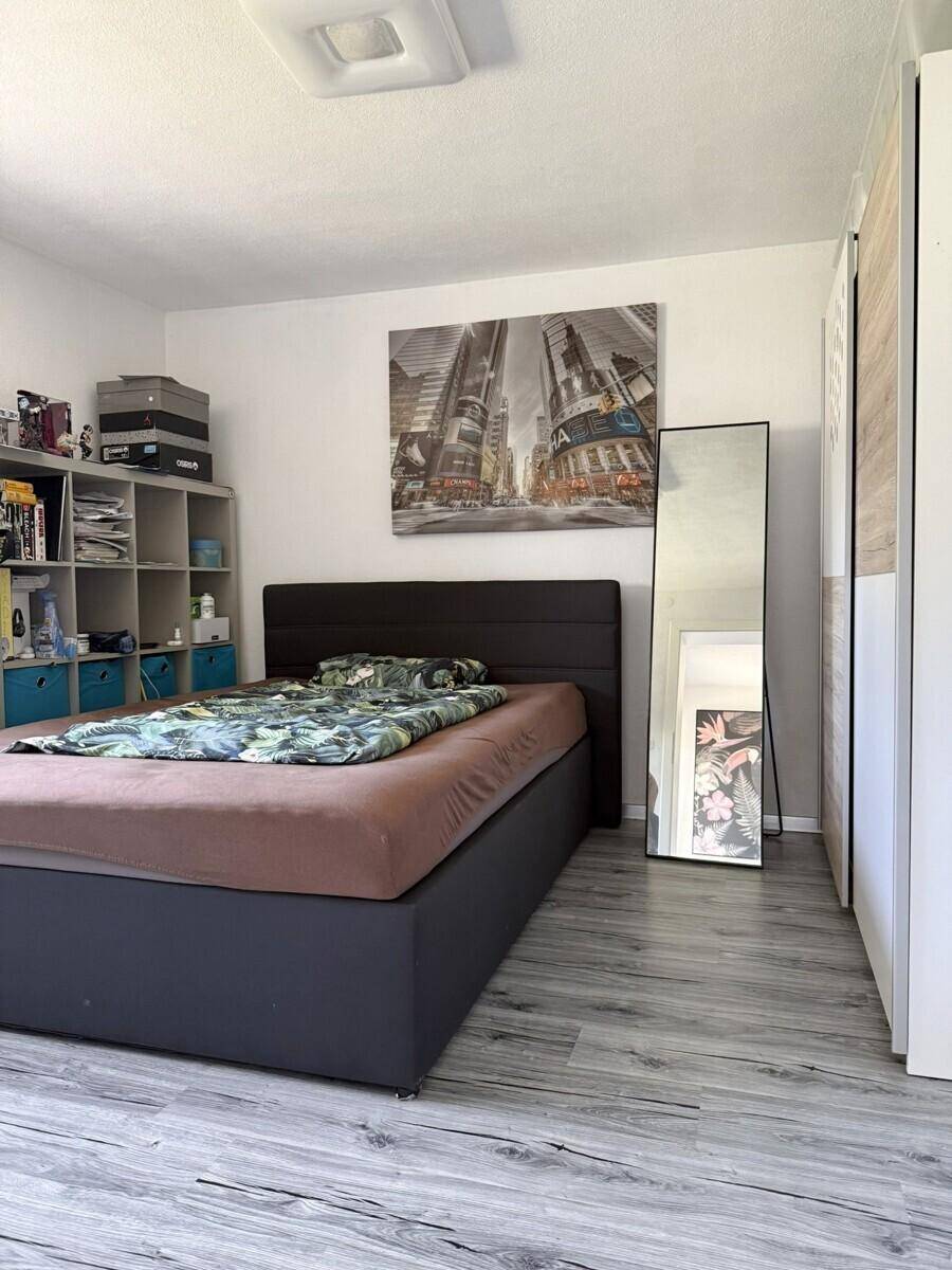 Schlafzimmer mit modernem Bett, Regalsystem und hellem Laminatboden.