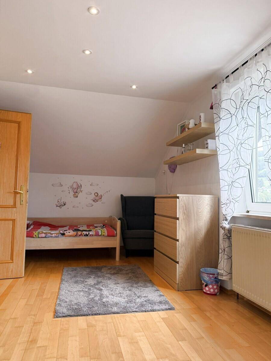 Kinderzimmer mit Holzboden, Einzelbett und Dachschräge, hell und freundlich gestaltet.