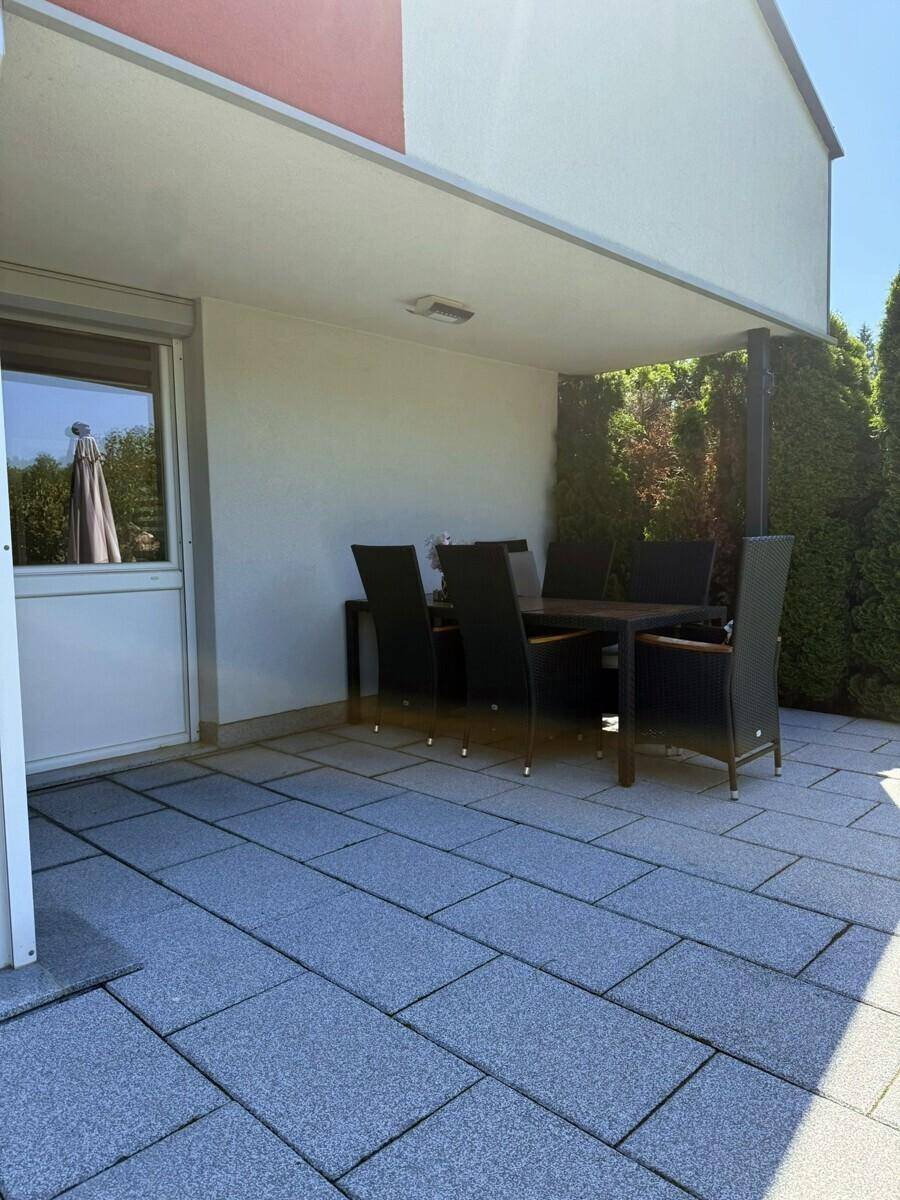 Überdachte Terrasse mit Esstisch und Stühlen, ideal für Mahlzeiten im Freien.