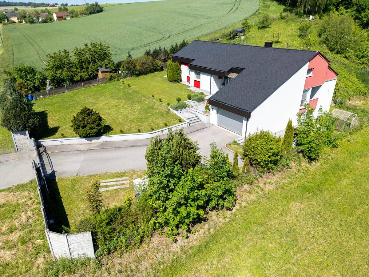 Luftaufnahme des Hauses mit Vorgarten, Auffahrt und ländlicher Umgebung.