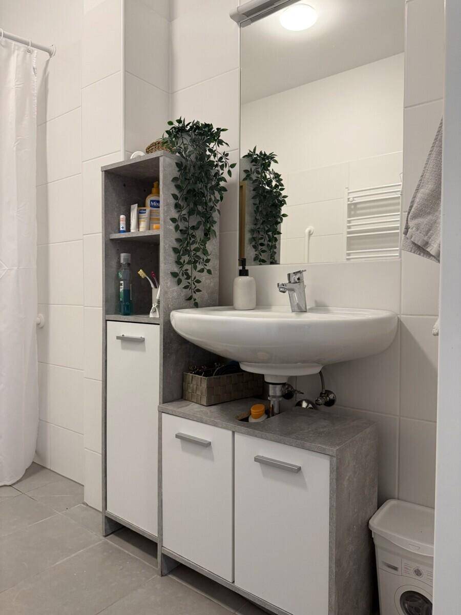 Modernes Badezimmer mit Waschbecken, Spiegel und praktischem Stauraum.