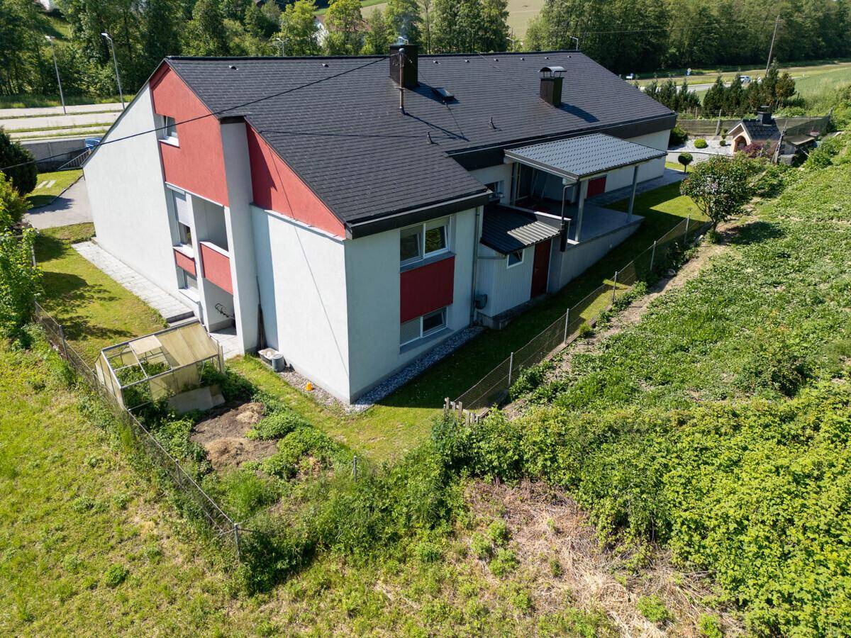 Rückansicht des Hauses mit Garten, Gewächshaus und angrenzender Natur.