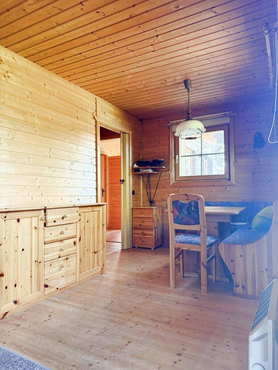 Gemütlicher Essbereich mit Holztisch, Eckbank und Holzvertäfelung, durch ein Fenster erhellt.
