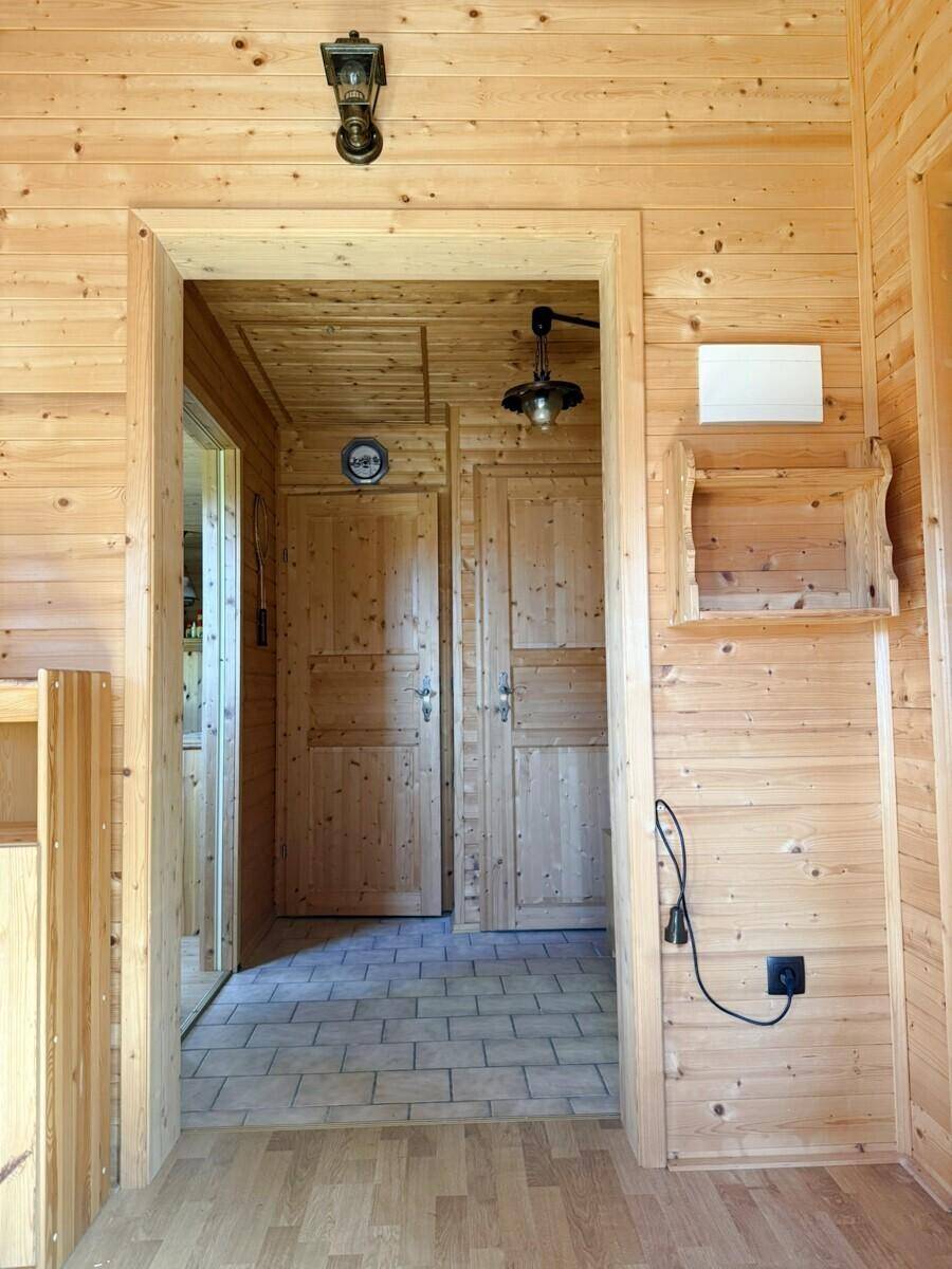Flur mit Holzvertäfelung an Wänden und Decke, gefliestem Boden und traditionellen Holztüren.