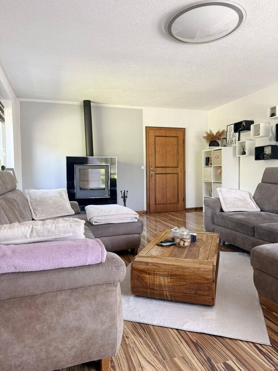 Gemütliches Wohnzimmer mit Kaminofen, bequemen Sofas und Holztisch.