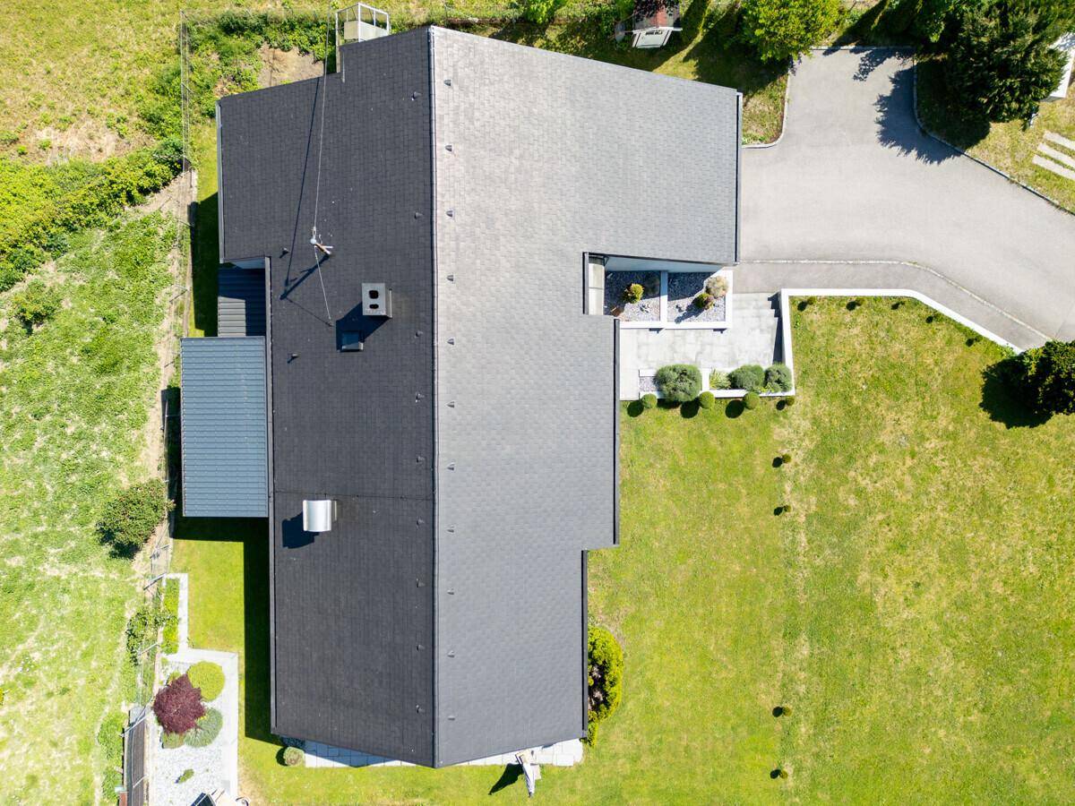 Vogelperspektive des Hauses mit dunklem Dach und weitläufigem Grundstück.