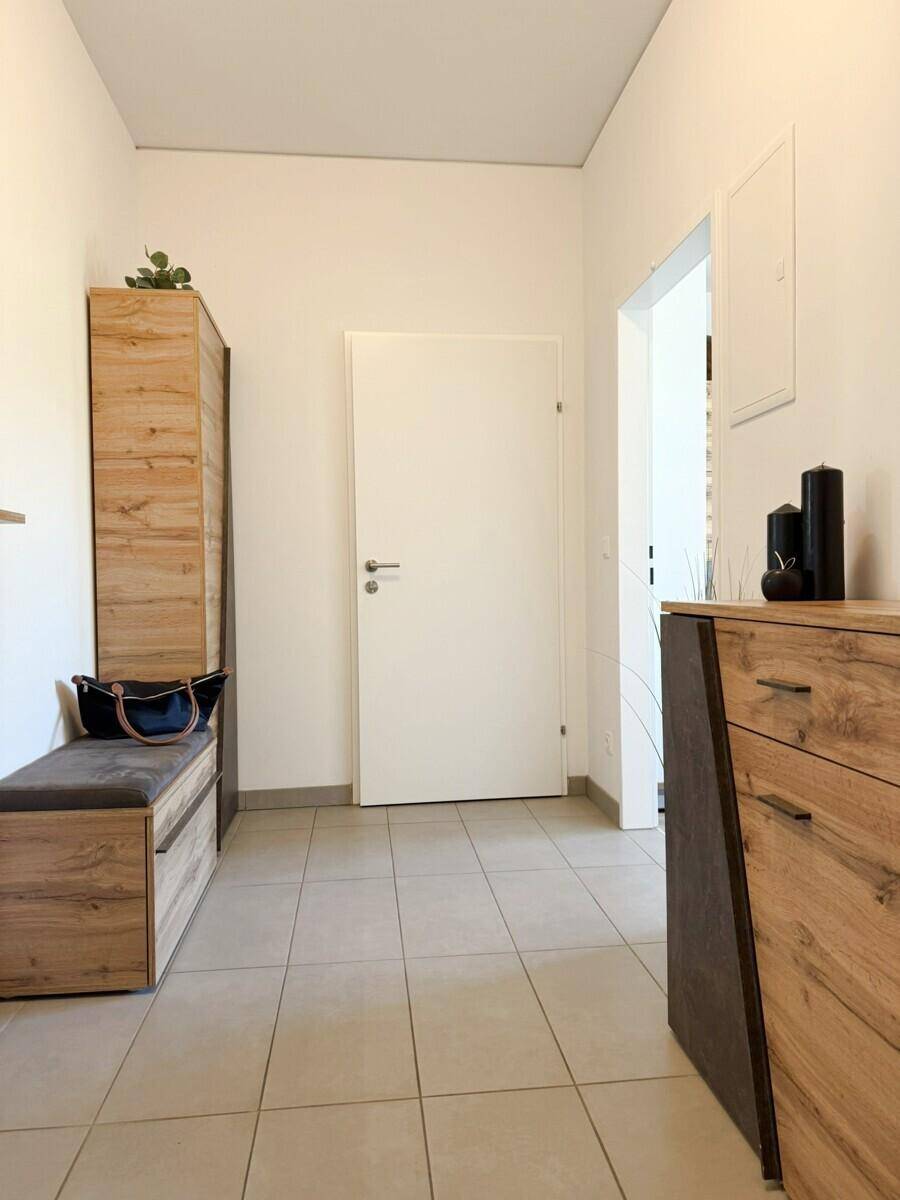 Heller Eingangsbereich mit Fliesenboden und Holzmöbeln, bietet Stauraum.