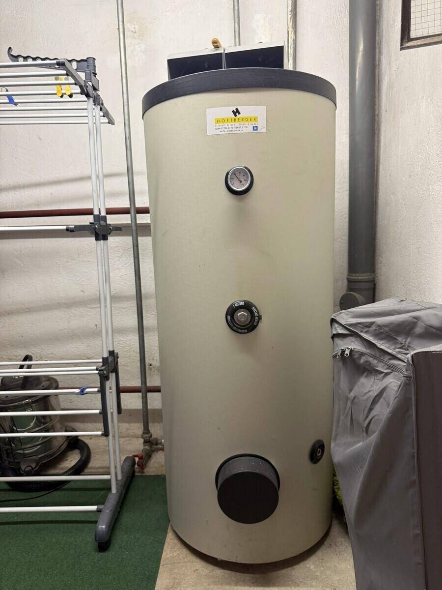 Hauswirtschaftsraum mit großem Warmwasserspeicher und Wäscheständer.
