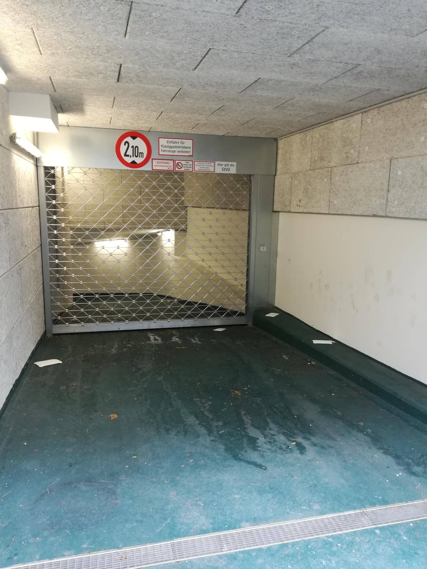 Einfahrt zu einer Tiefgarage mit Rolltor und Höhenbegrenzung von 2,10 Metern.