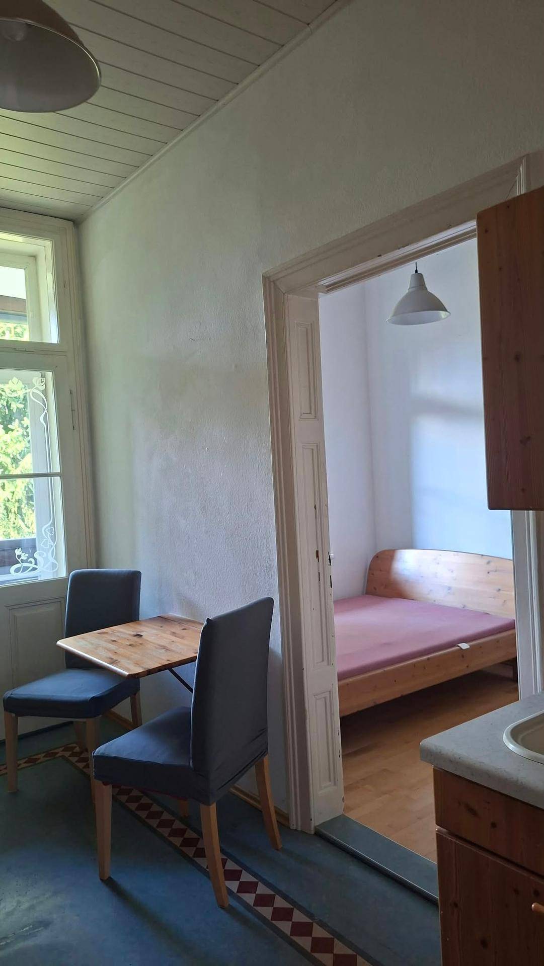 Kleiner Essbereich mit Holztisch und Stühlen, mit Blick in ein angrenzendes Schlafzimmer.
