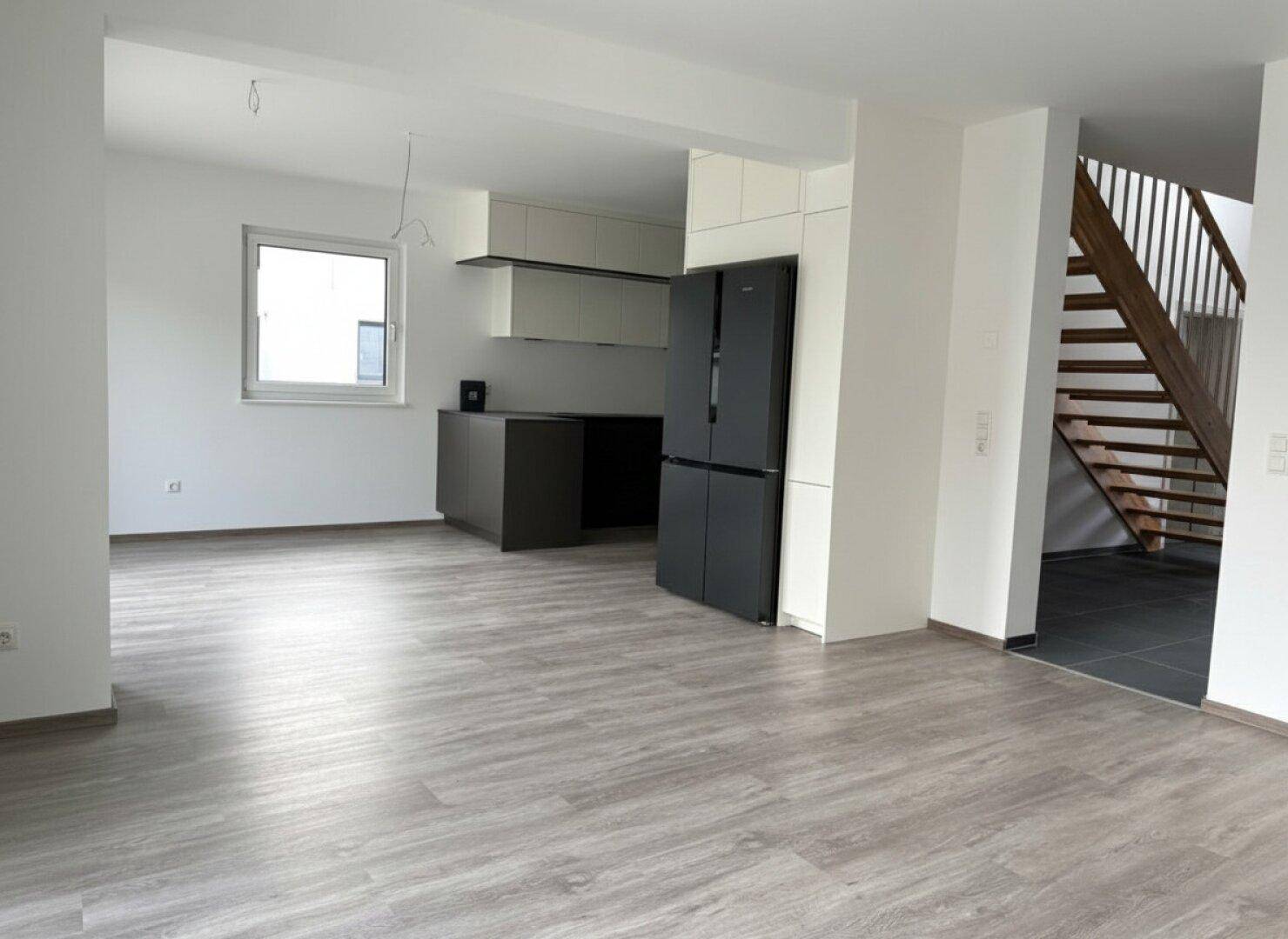 Offener Küchenbereich mit modernem Design, integriertem Kühlschrank und Blick auf den Wohnraum.