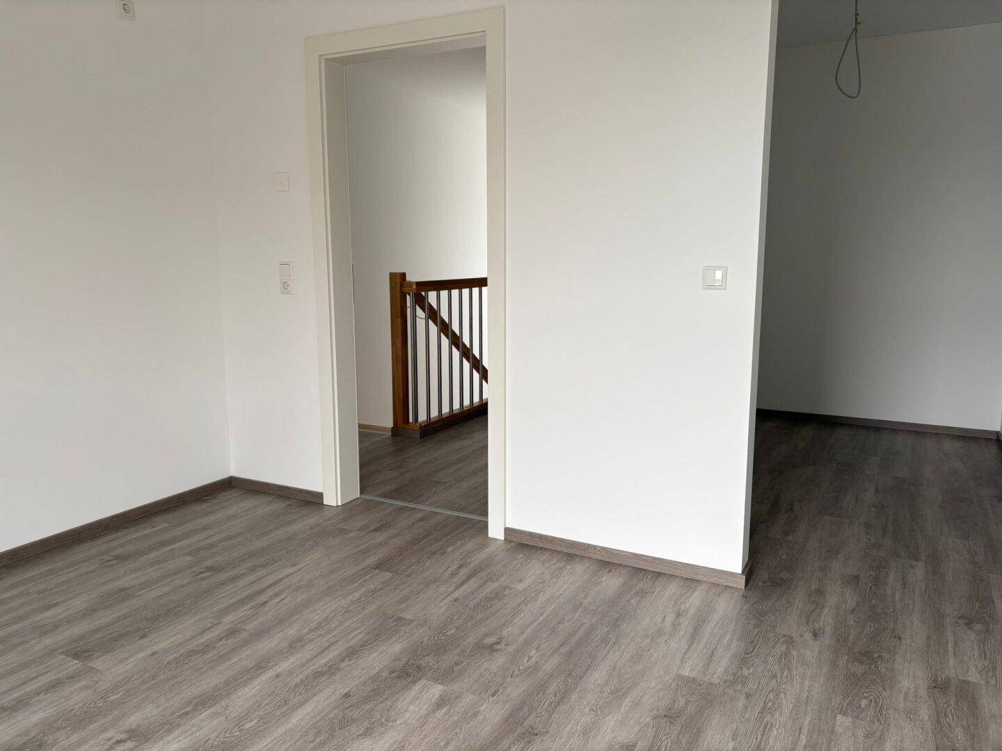 Heller Flur mit Laminatboden und Holztreppe, die in die obere Etage führt.